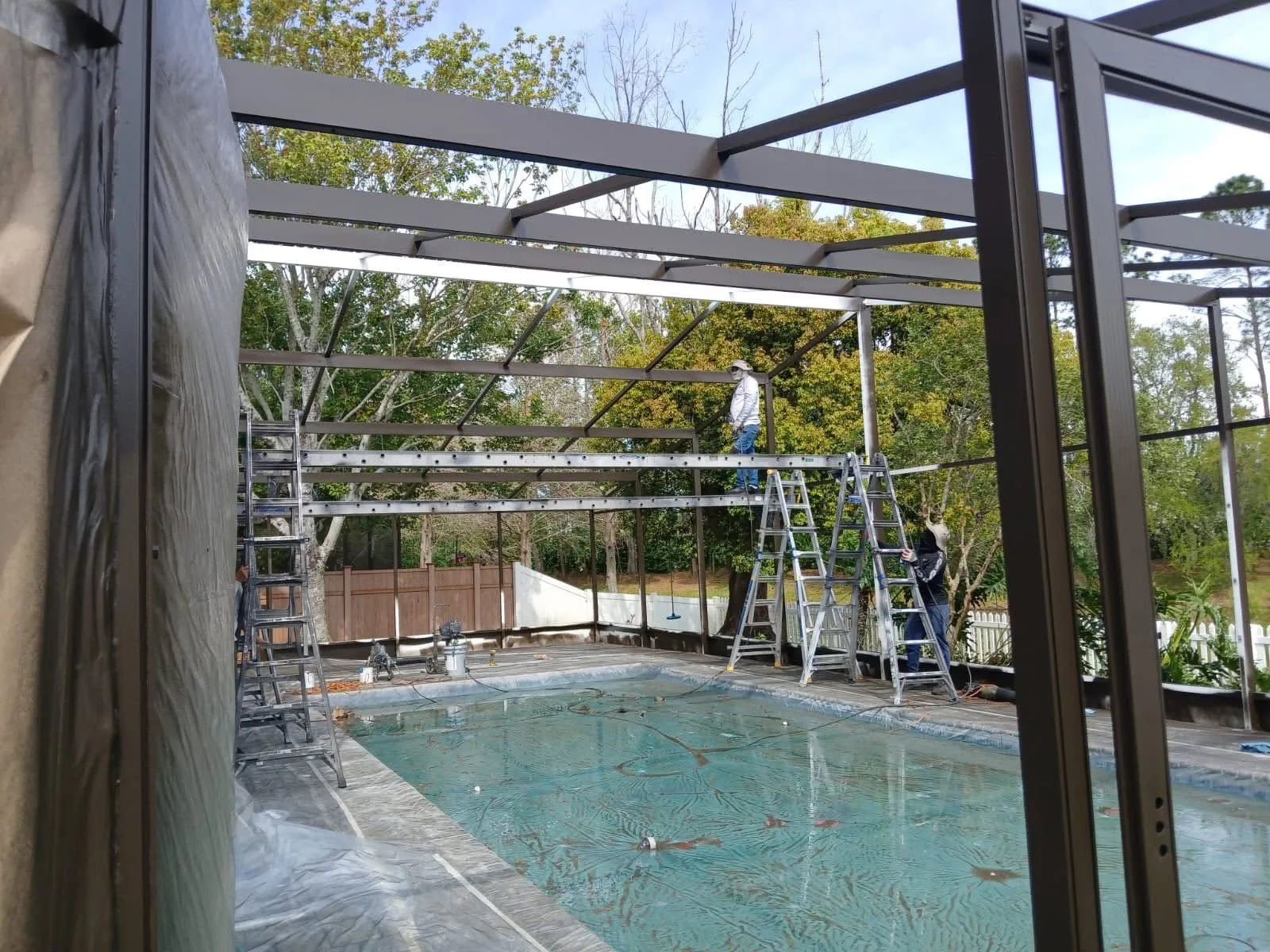Technicians working on a pool enclosure rescreening project