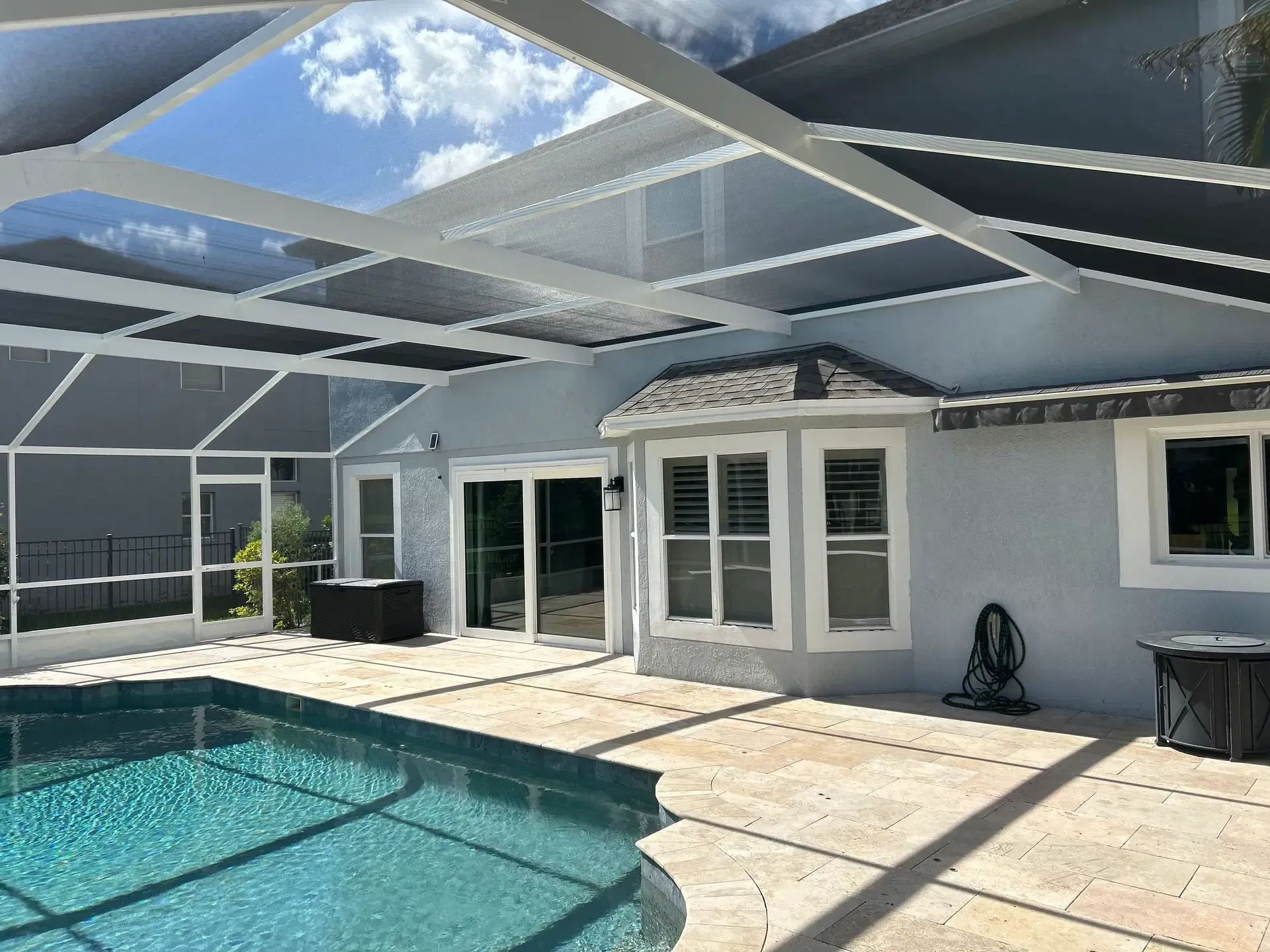 White-framed pool enclosure with taut dark screens and a clean patio finish